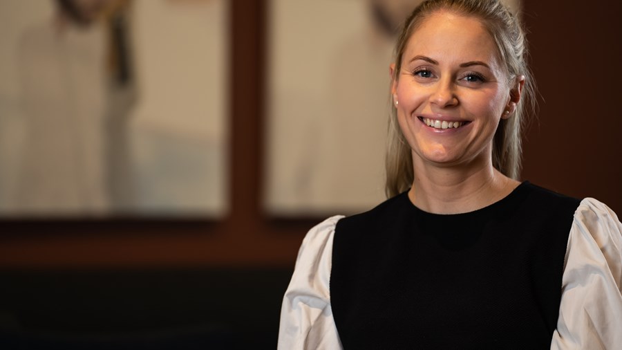 Kvinne med langt lyst hår smiler mot kamera.